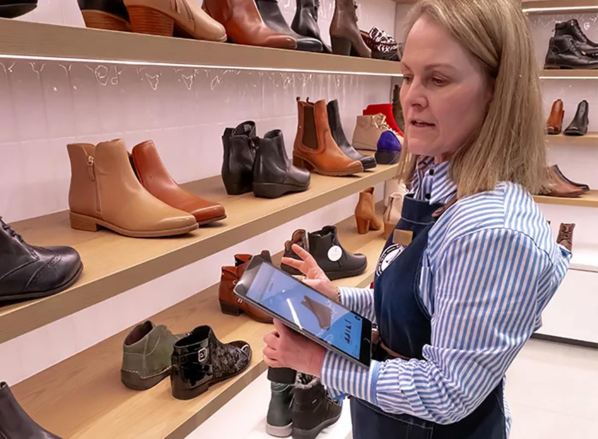 Store staff with portable tablet stand in store at Munro Footwear Group