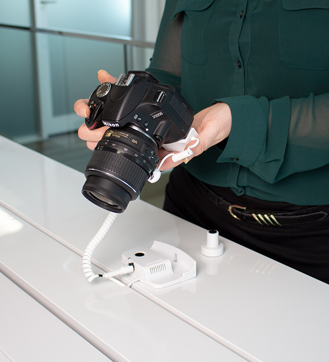 Person holding camera with security attached to Nikon camera, retail